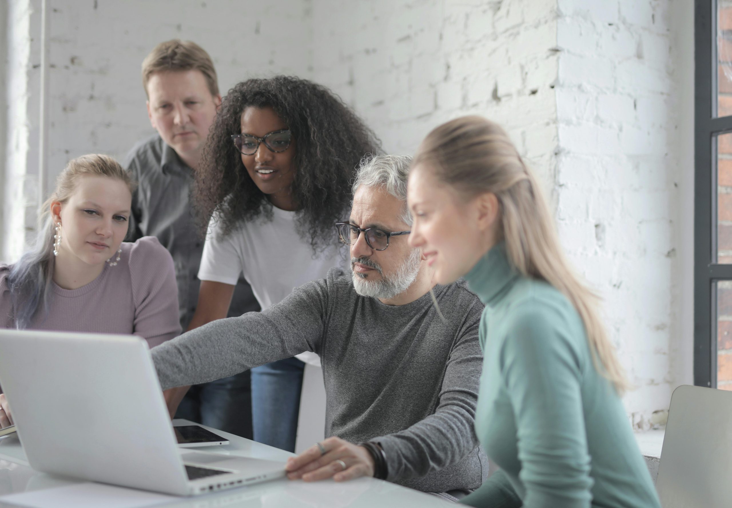 Eine Gruppe von Mitarbeitenden vor einem Laptop, die auf den Bildschirm sehen. (C) Andrea Piacquadio / Pexels